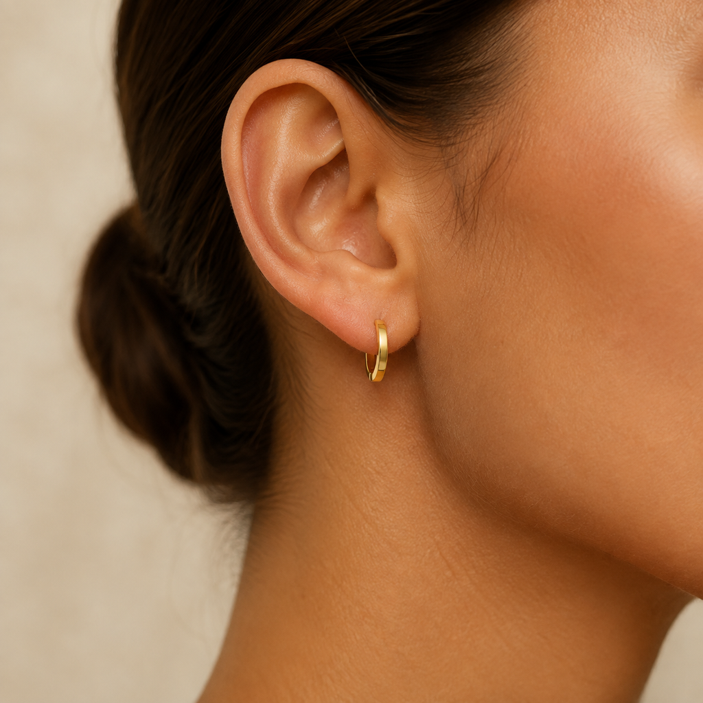 Aros Huggie Nova dorados puestos en la oreja